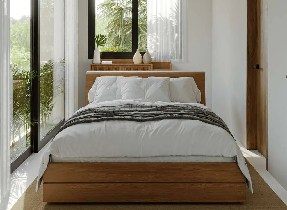 Bedroom with a low timber bed, white linen and a window onto planting.